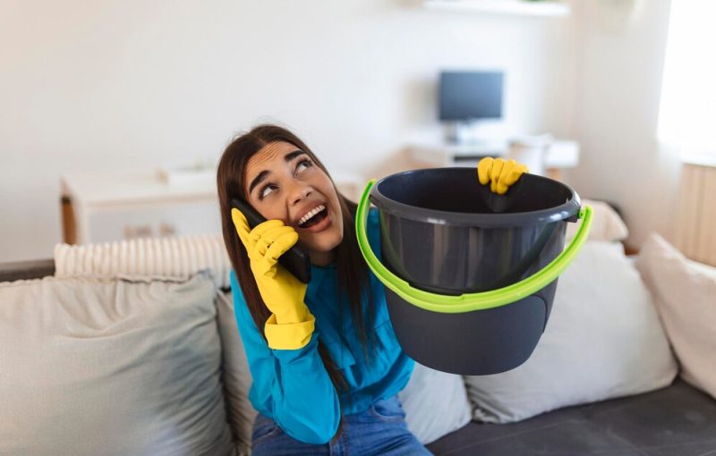 shocked-woman-calling-plumber-while-collecting-water-leaking-from-ceiling-using-utensil_657921-1199